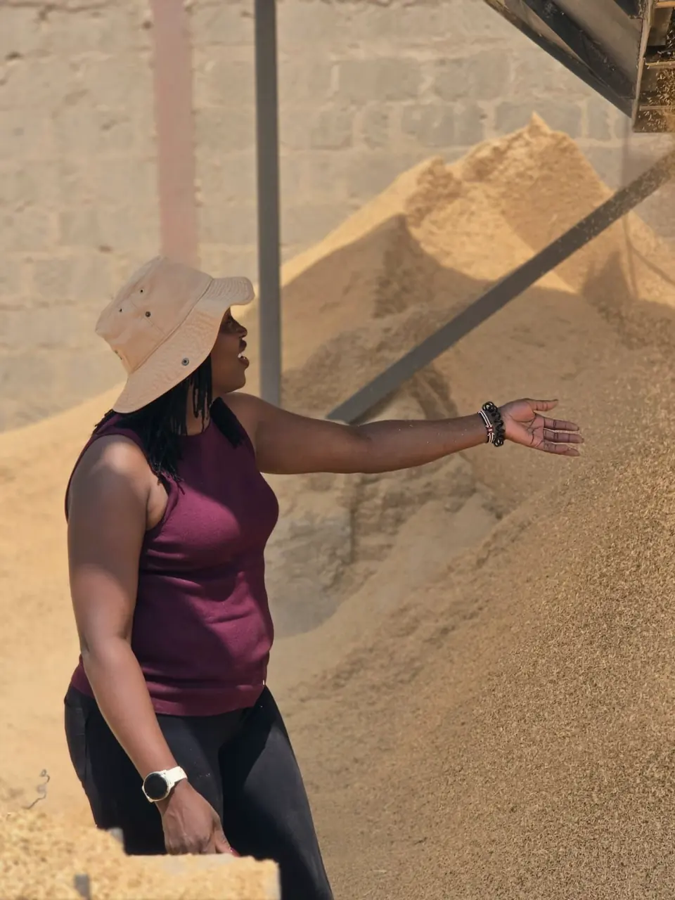 A member of the ENKOP team gestures towards a large pile of rice husk falling from a chute at MGM Rice Mill.