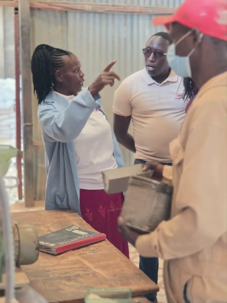 A partner technical officer briefs members of the ENKOP team across a workbench.