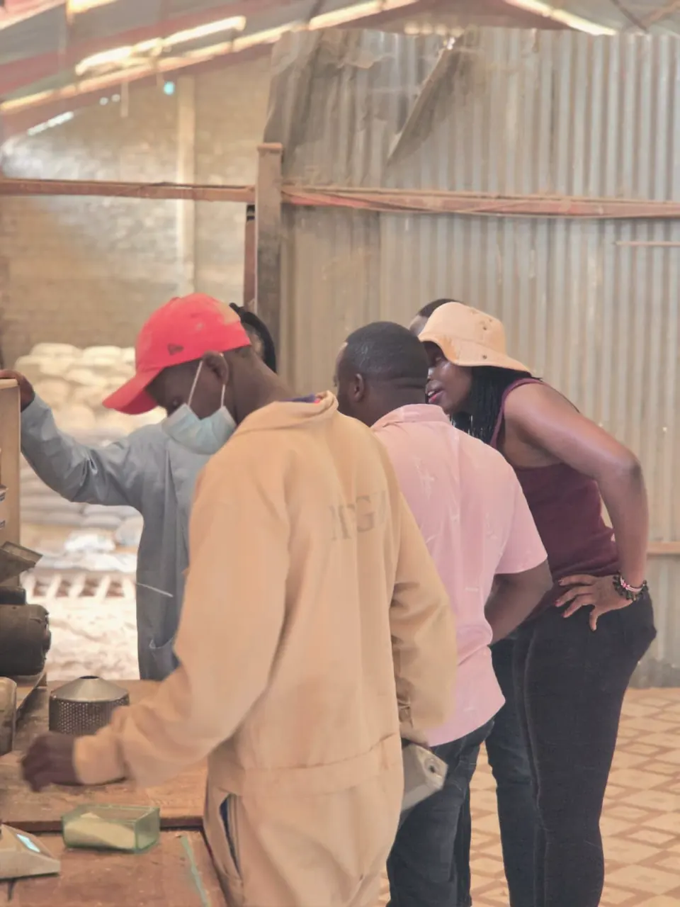 ENKOP team members and partner technical staff lean over a workbench to examine samples.